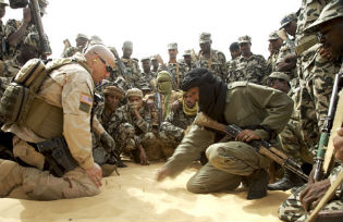 A U.S. Special Forces soldier instructs Malian troops in counterterrorism tactics through a translator (right, in black turban) on the outskirts of Timbuktu. Photographs by Justin Bishop (2007).