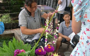 Local women from the ancient city of Huanglongxi making flower garlands to sell as headgear to protect the wearer from the sun.